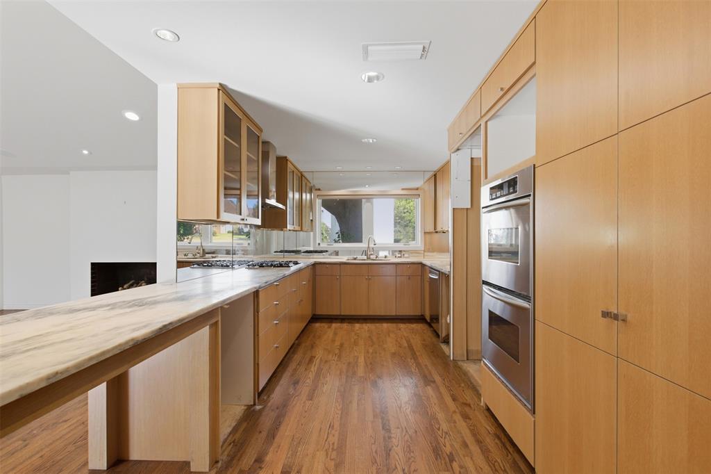 Kitchen featuring flat-panel wood cabinetry, natural stone countertops, hardwood flooring, recessed lighting, and stainless steel double wall ovens