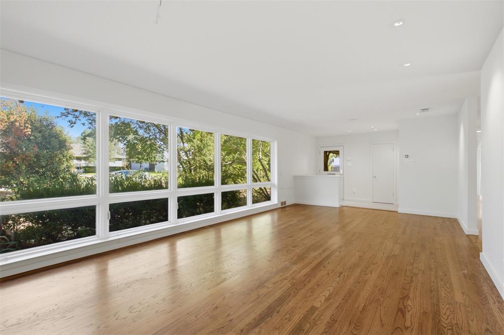 Expansive living area featuring wood-finish flooring, extensive floor-to-ceiling windows, and recessed lighting