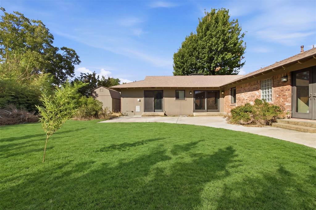 Backyard featuring a concrete patio, exterior brick masonry, sliding glass doors, and a detached storage shed