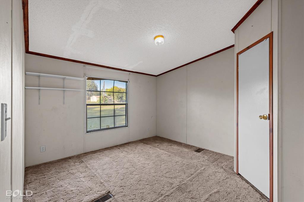 Interior room featuring neutral wall finishes, carpeting, a single-pane window with a grid pattern, built-in shelving, and a wood-trimmed interior door