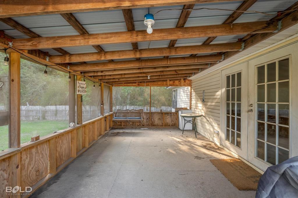 Screened-in porch featuring a concrete floor, exposed timber rafters, and double-paned glass doors