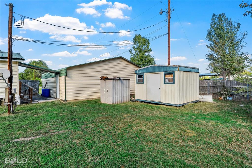 Outdoor space featuring a detached metal garage, a storage shed, and a wood-slat privacy fence