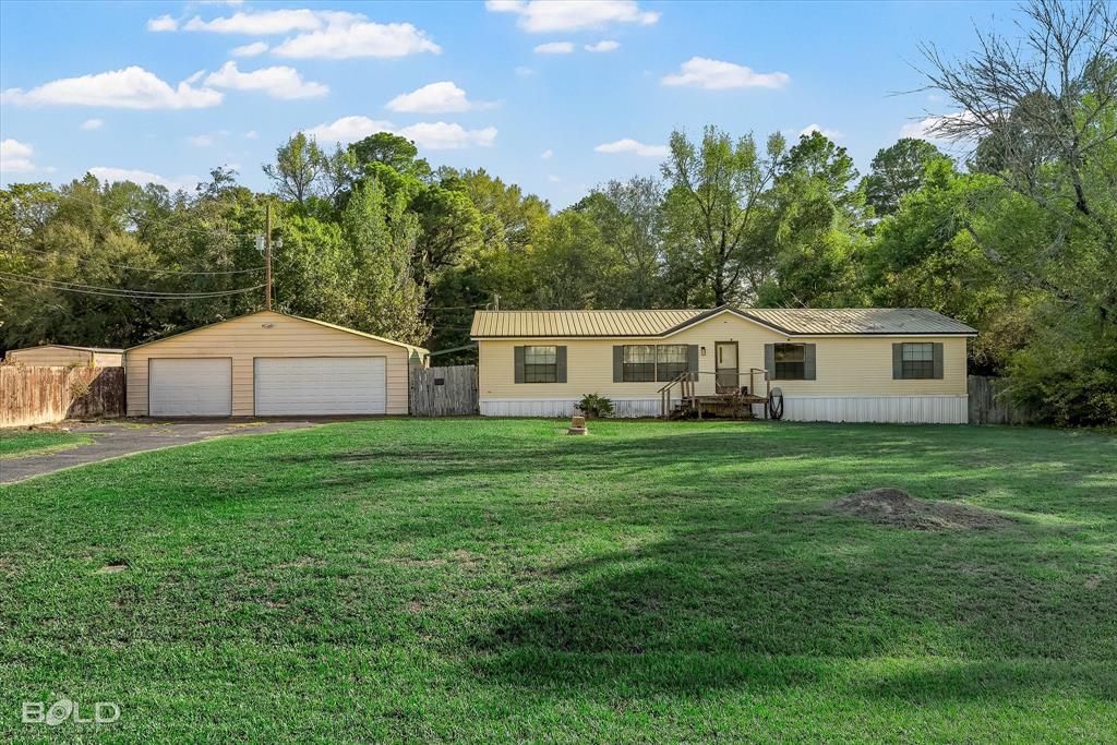 Single-story residence featuring horizontal siding, a standing seam metal roof, and a detached THREE-car garage situated on a grass-covered lot