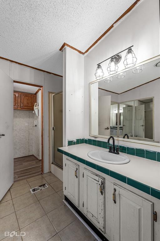 Bathroom vanity featuring a white cabinet base, tile countertop with a green tiled backsplash, integrated oval sink, and dark metal faucet, accompanied by a large wall-mounted mirror and a three-light fixture