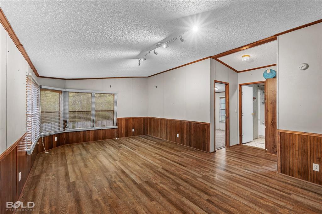 Room featuring wood-finish flooring, wood wainscoting, bay window, and adjustable track lighting
