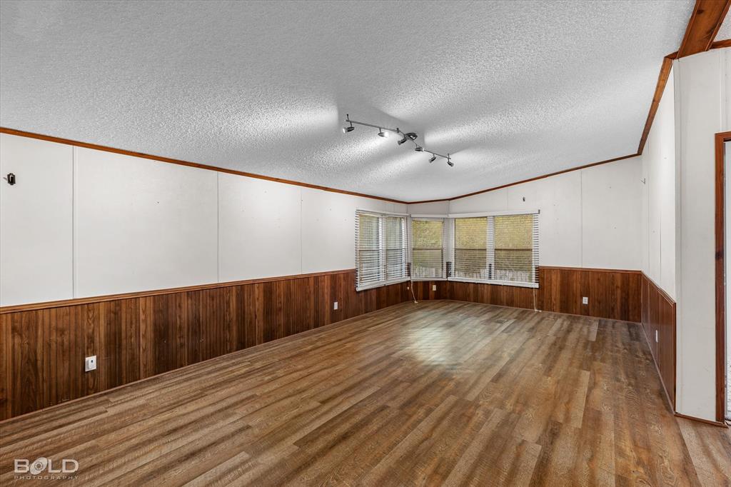 Wood-finish flooring, wood panel wainscoting, bay window configuration, and track lighting