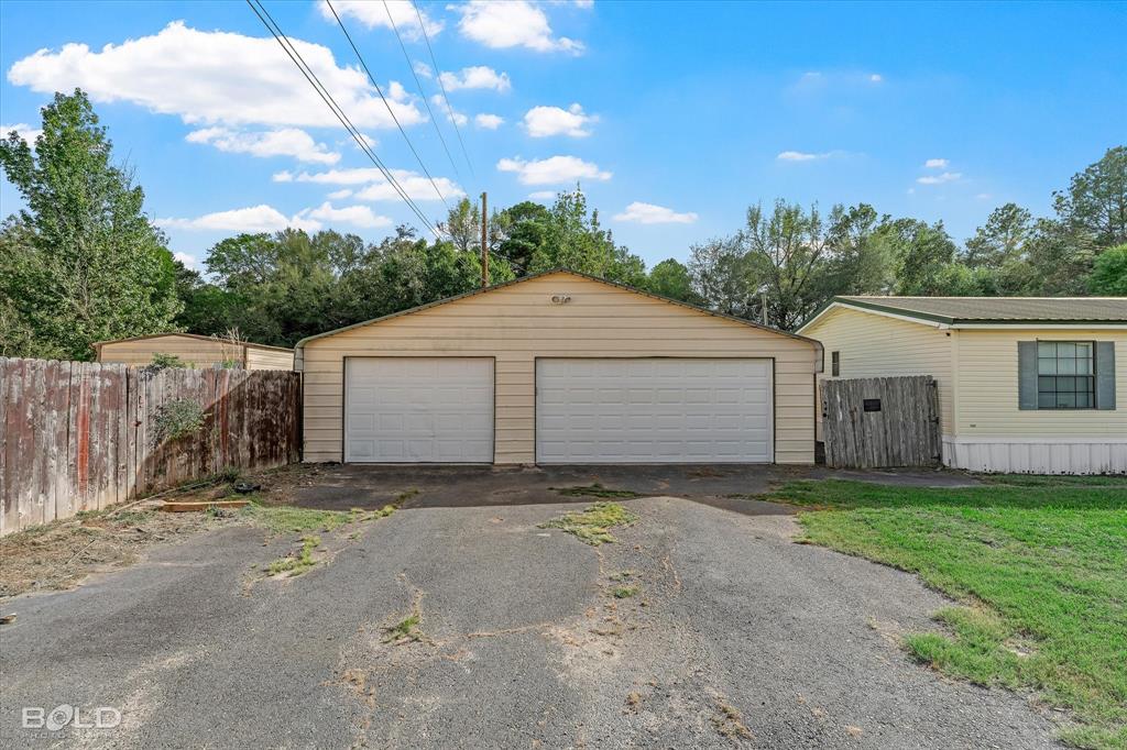 Detached two-car garage with dual overhead doors, horizontal siding, and an asphalt driveway