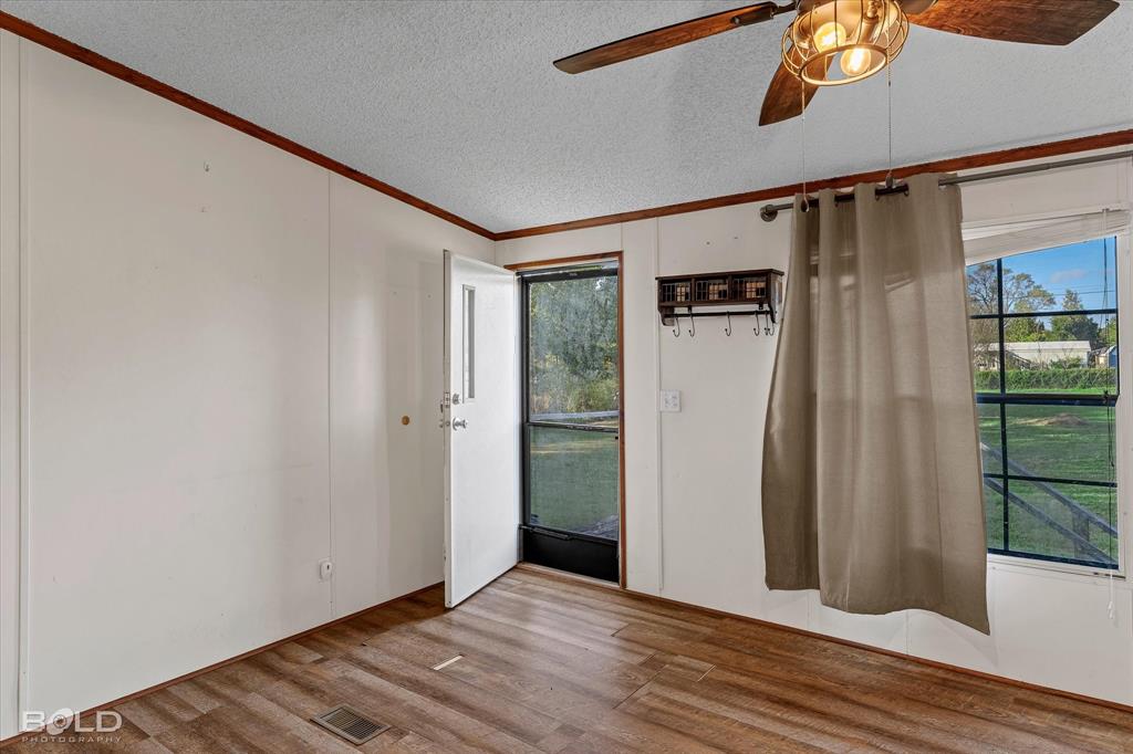 Wood-finish flooring, ceiling fan with integrated lighting, multi-lite window, and wall-mounted storage rack