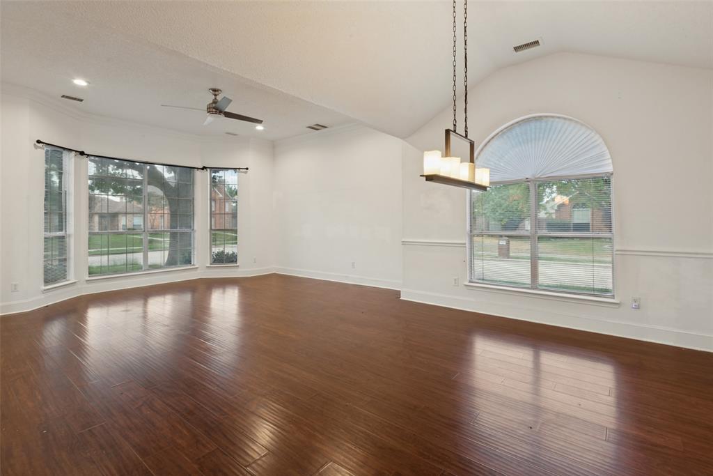 Vaulted ceiling, wood-finish flooring, bay window, arched window, and linear multi-light pendant fixture Vaulted ceiling, wood-finish flooring, bay window, arched window, and linear multi-light pendant fixture
