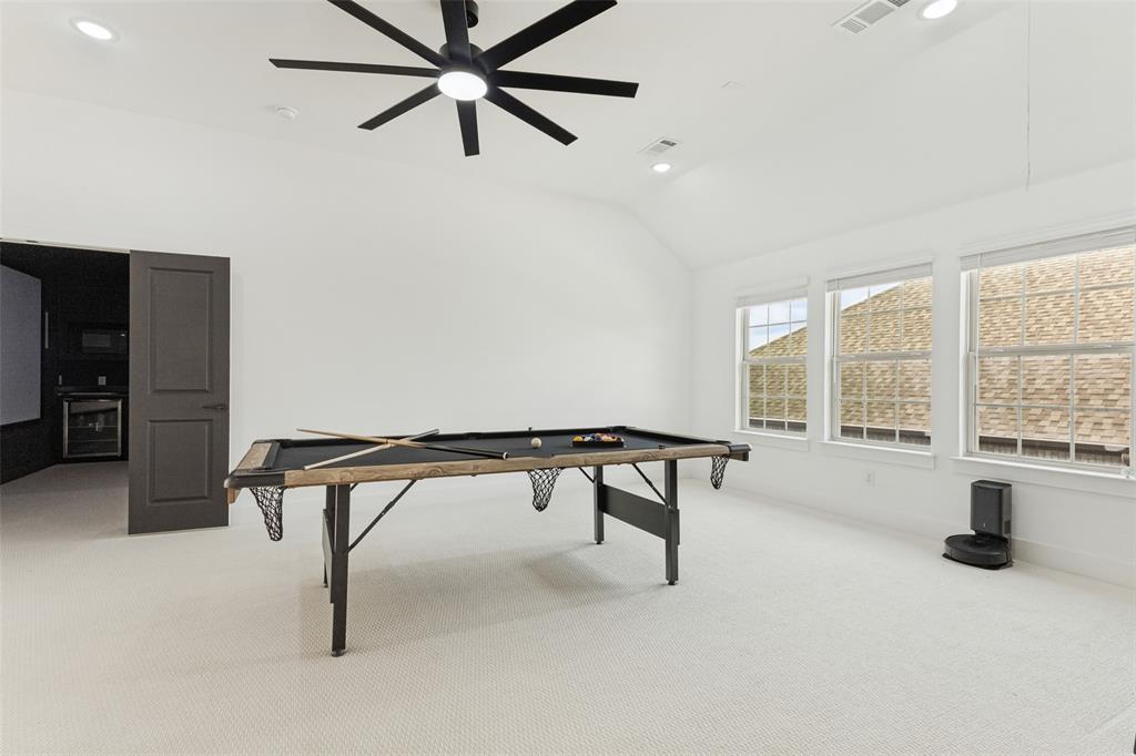 Vaulted ceiling featuring a multi-blade ceiling fan with integrated lighting, recessed lighting, neutral wall-to-wall carpeting, and triple-paned windows