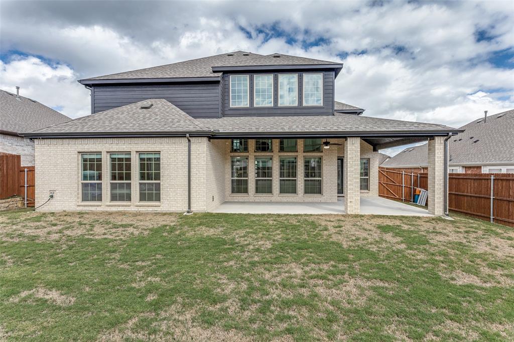 Two-story exterior featuring light brick masonry, dark horizontal lap siding, a covered concrete patio, and a shingle roof