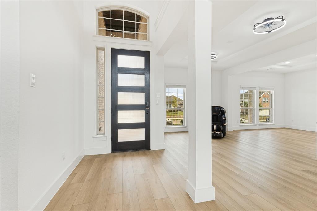 Entryway featuring wood-finish flooring, a contemporary multi-panel front door with horizontal glass inserts, an arched transom window, side-light window panel, and modern ceiling-mounted fixtures