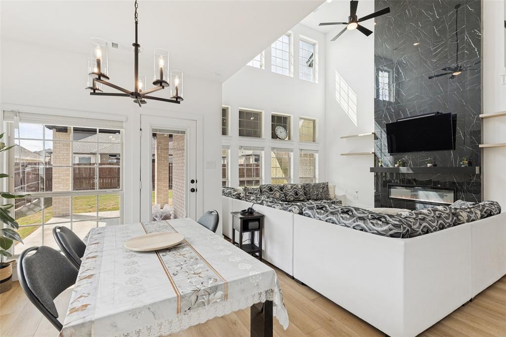 Double-height ceiling, floor-to-ceiling stone-finish fireplace surround, wood-finish flooring, metal multi-light chandelier, and expansive grid-pane windows