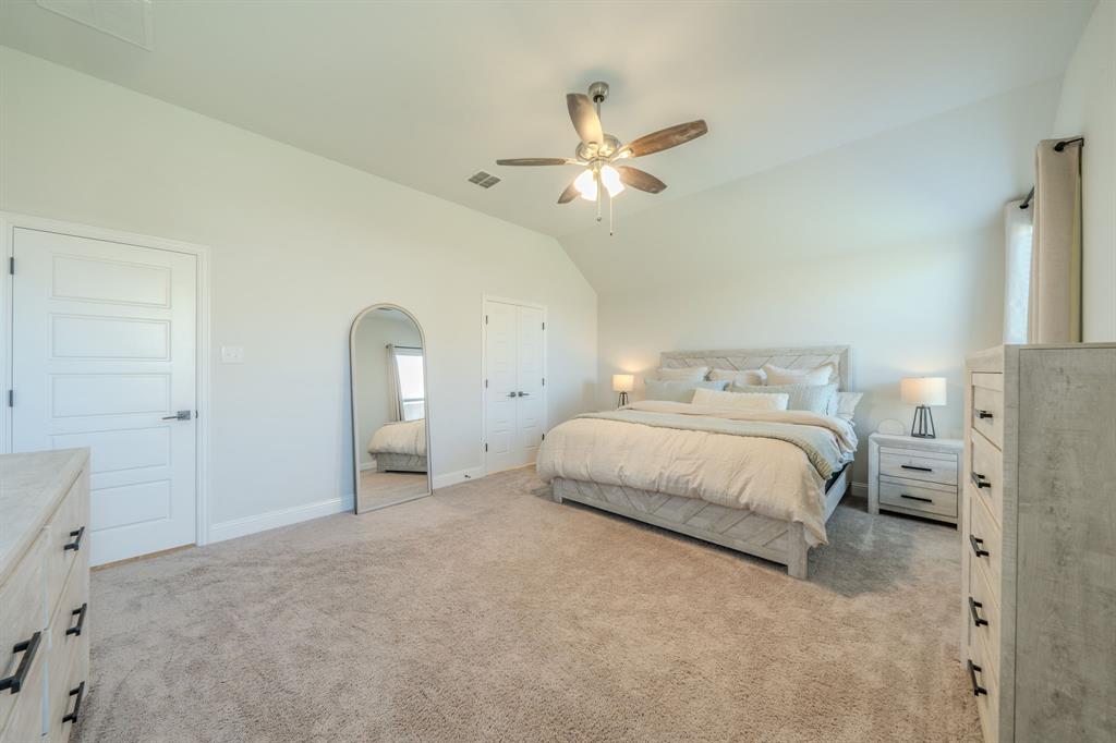 Vaulted ceiling featuring a central multi-blade ceiling fan with integrated lighting and neutral wall-to-wall carpeting
