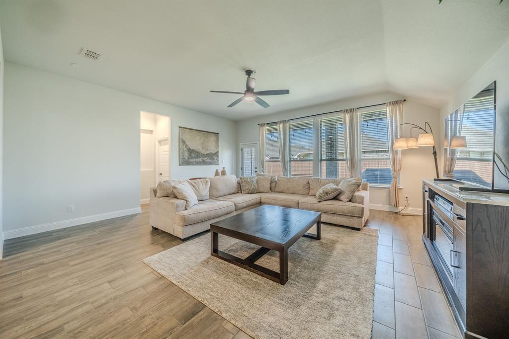 Living area featuring vaulted ceilings, wood-finish tile flooring, and oversized windows