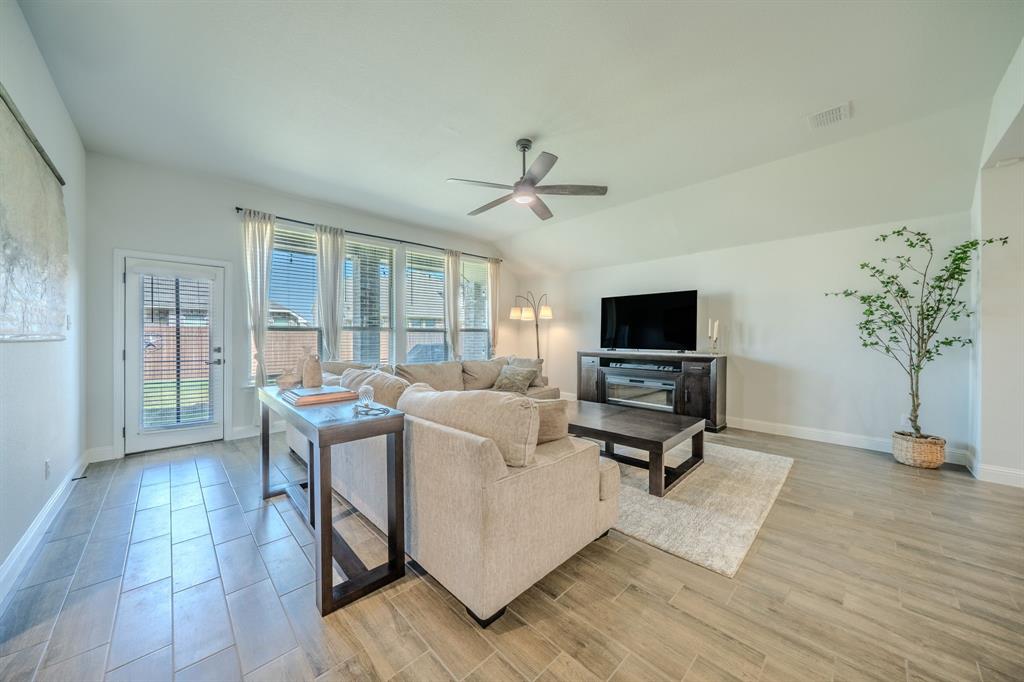 Vaulted ceilings, wood-finish tile flooring, recessed lighting, ceiling fan, and large windows