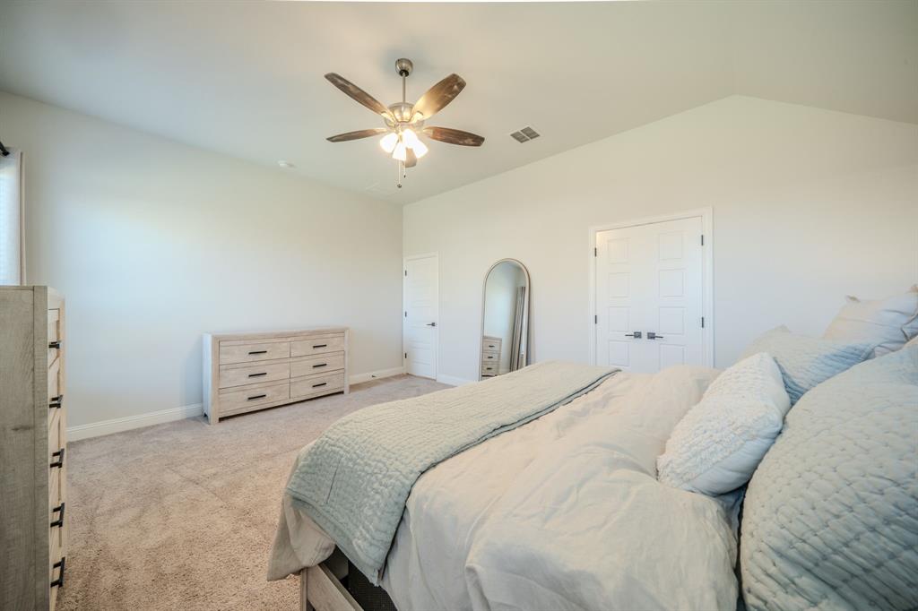 Vaulted ceiling, neutral wall tones, carpeted flooring, and a multi-blade ceiling fan with integrated lighting
