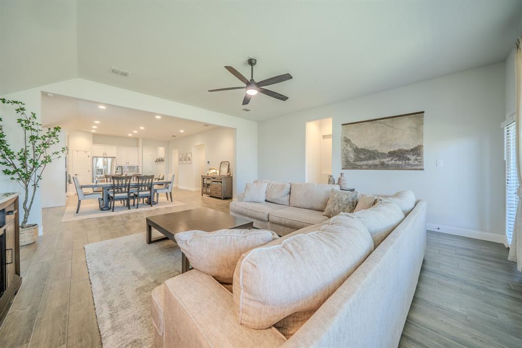 Vaulted ceilings, wood-finish flooring, recessed lighting, and a multi-blade ceiling fan
