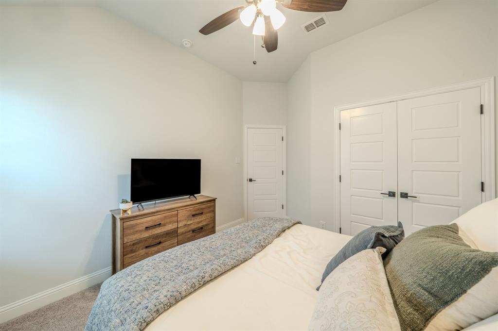 Vaulted ceilings, carpeted flooring, and a multi-blade ceiling fan with integrated lighting