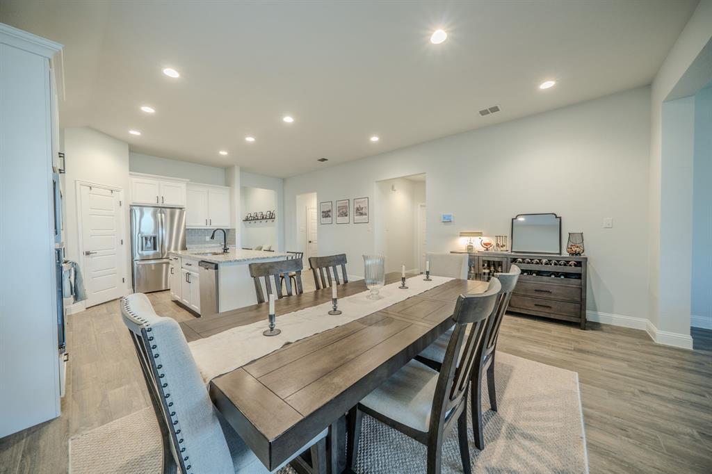 Kitchen featuring white cabinetry, stone countertops, stainless steel appliances, and wood-finish flooring throughout