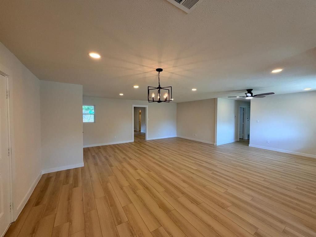 Open interior space featuring wood-finish flooring, recessed lighting, a modern geometric chandelier, and a ceiling fan with integrated lighting