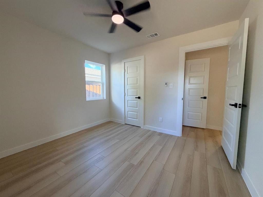 Interior room featuring wood-finish flooring, five-panel doors with matte black hardware, and a ceiling-mounted light fixture with fan blades