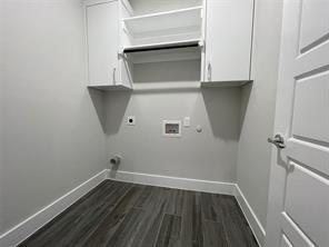 Utility room featuring wood-finish flooring, white upper cabinetry, and an integrated hanging rod
