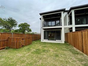 Two-story exterior featuring a covered upper-level balcony with metal railing, a lower-level patio, and a privacy-fenced backyard