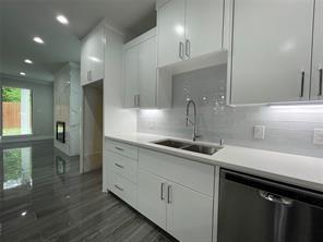Kitchen featuring high-gloss white cabinetry, quartz countertops, a stainless steel undermount sink with a gooseneck faucet, light-toned subway tile backsplash, and polished stone-finish flooring