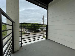 Covered balcony featuring horizontal metal railings, white horizontal siding, painted brick pillar, and solid flooring