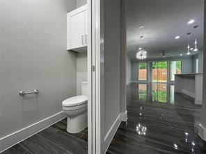 Powder room featuring a dual-flush toilet, wall-mounted cabinetry, dark wood-finish tile flooring, recessed lighting, and expansive sliding glass doors