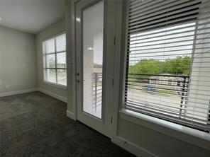 Interior space featuring wall-to-wall carpeting, multiple windows with horizontal blinds, and a glass-paneled exterior door