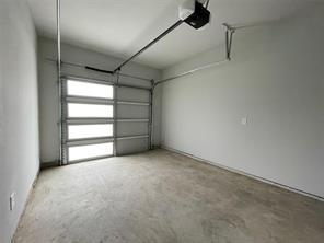 Attached garage featuring concrete flooring, smooth-finished walls, and an overhead sectional door with integrated glass panels