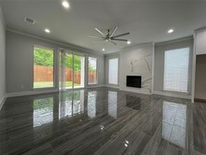 Living area featuring large-format polished tile flooring, floor-to-ceiling stone-surround fireplace, recessed lighting, brushed metal ceiling fan, and multi-panel sliding glass doors