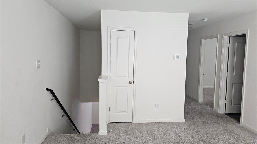Neutral-toned wall-to-wall carpeting, staircase with a black handrail, solid-core interior doors, and white-painted interior walls