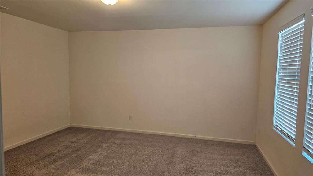 Neutral-toned carpeted flooring, light-colored walls, and two windows with horizontal blinds