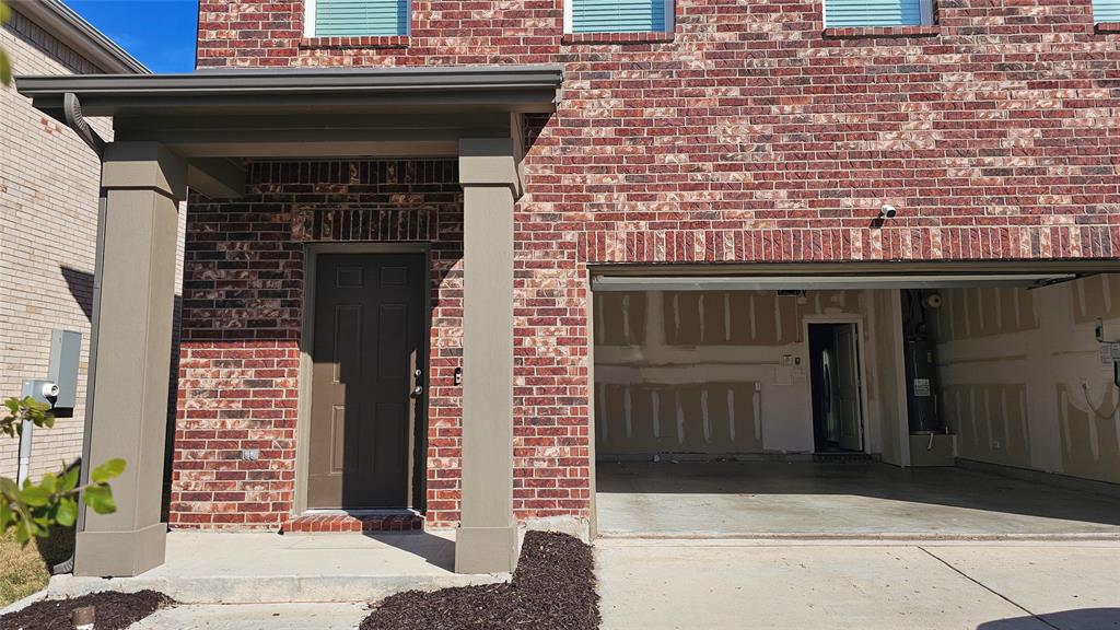Exterior featuring multi-tonal brick masonry, a covered porch with concrete foundation, two structural pillars, and a concrete driveway leading to a two-car garage Exterior featuring multi-tonal brick masonry, a covered porch with concrete foundation, two structural pillars, and a concrete driveway leading to a two-car garage