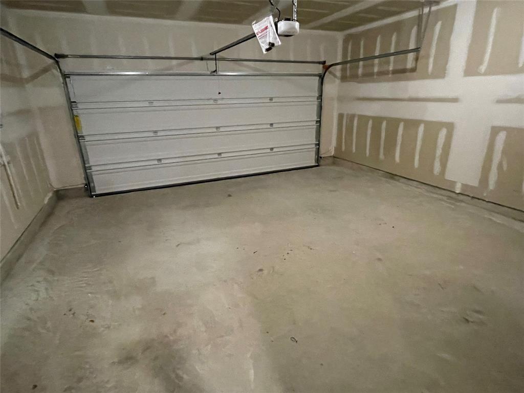 Garage featuring a sectional overhead door, concrete flooring, and unfinished drywall walls