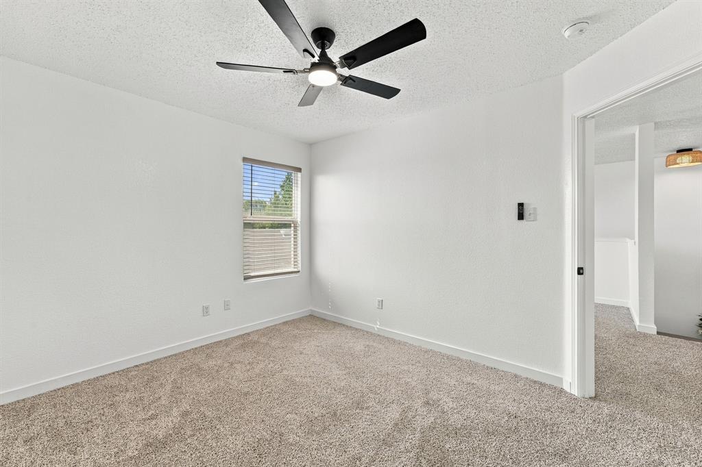 Room featuring neutral-toned carpeting, matte black ceiling fan with integrated lighting, and a single window with horizontal blinds