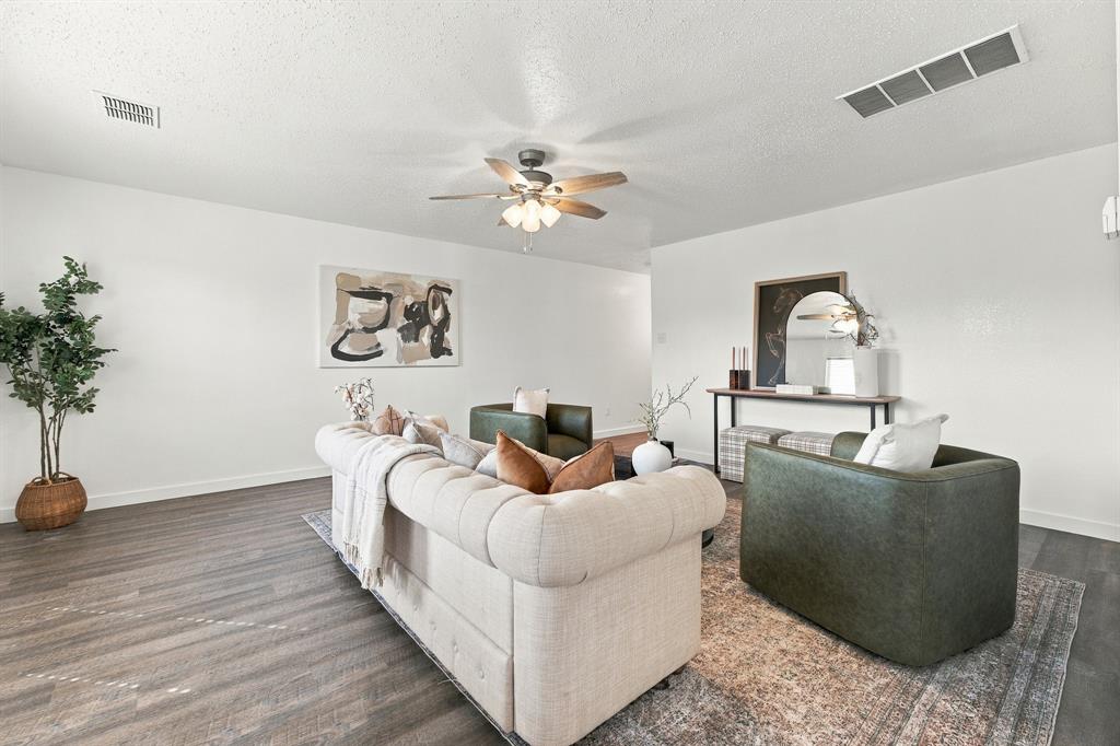 Neutral interior space featuring wood-finish flooring and a central ceiling fan with integrated lighting