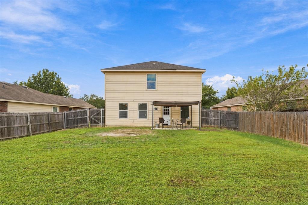 Rear exterior featuring horizontal lap siding, a covered concrete patio, and a fenced backyard