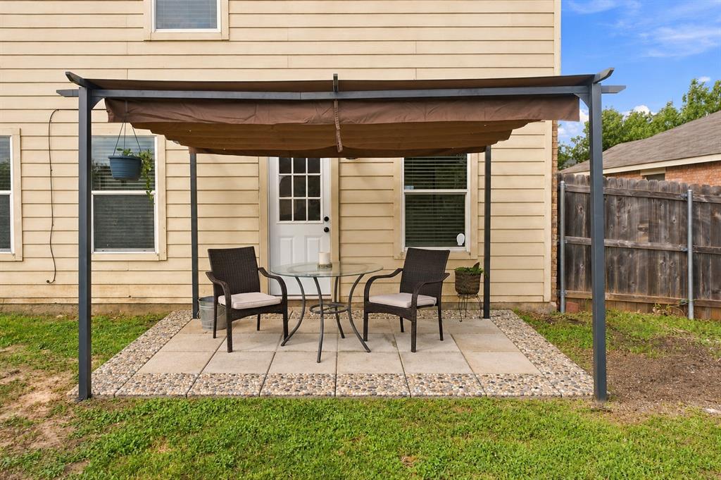 Backyard featuring a paved stone patio, metal-frame pergola with a fabric canopy, and horizontal lap siding exterior
