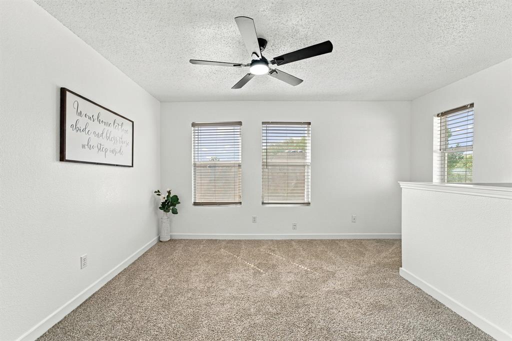 Neutral wall finish, wall-to-wall carpeting, ceiling fan with integrated lighting, and dual windows with horizontal blinds