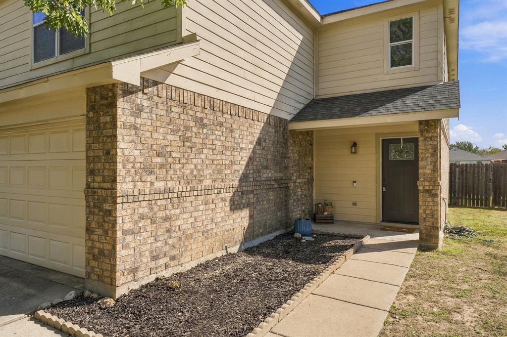 Two-story exterior featuring a brick and horizontal siding facade, a front-entry door with a decorative glass insert, a concrete walkway, and an attached garage