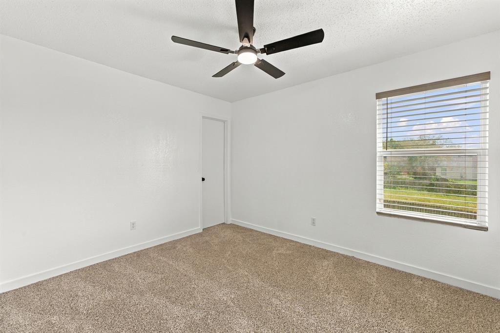 Neutral wall paint, plush carpeting, ceiling fan with integrated lighting, and horizontal window blinds