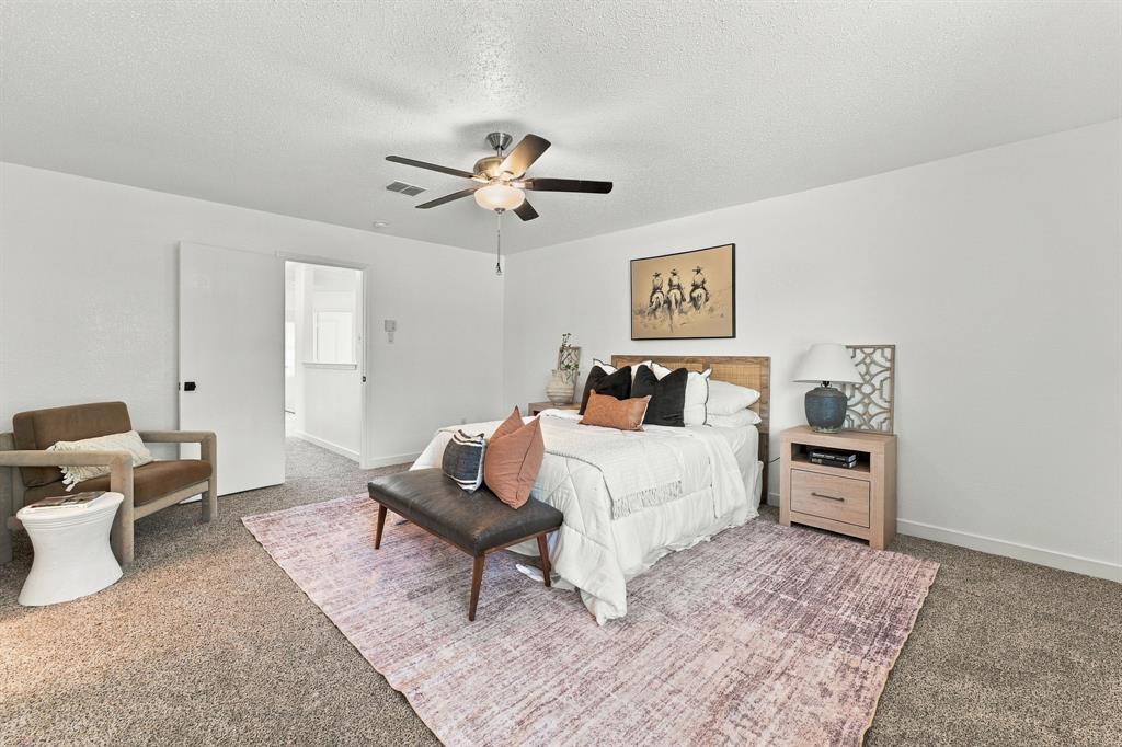 Spacious room featuring neutral carpeting, a central ceiling fan with integrated light fixture, and a solid-core interior door