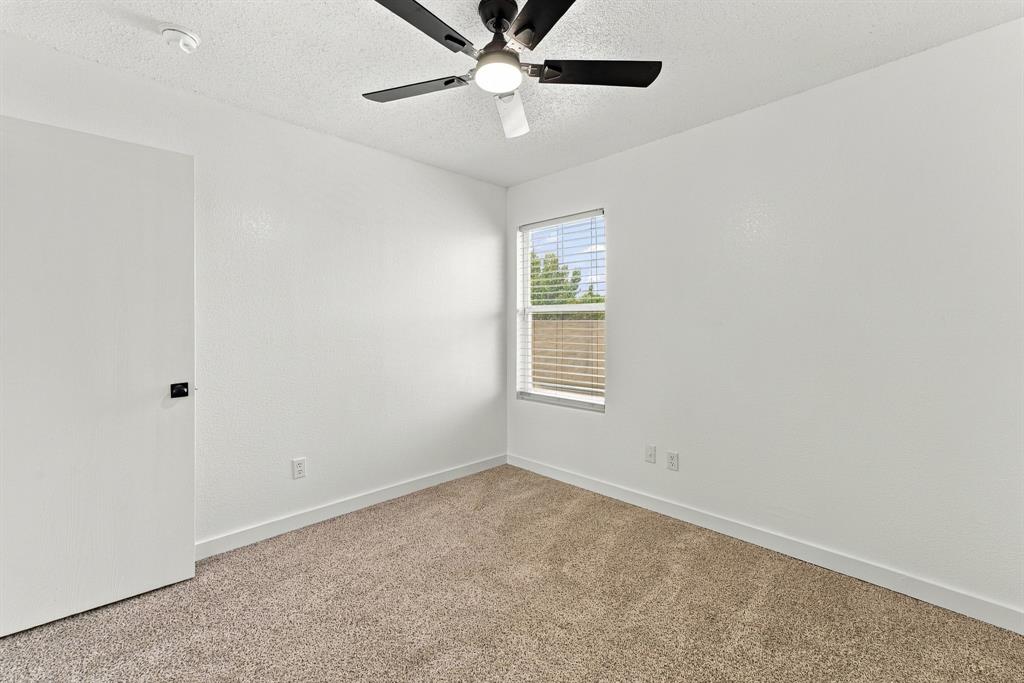 Neutral-toned carpeting, matte black ceiling fan with integrated light fixture, single-panel interior door with matte black hardware, and double-pane window