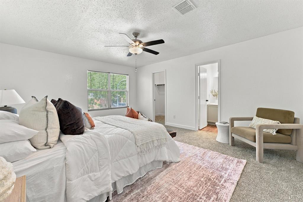 Bedroom featuring neutral carpeting, a multi-blade ceiling fan with integrated lighting, and a walk-in closet