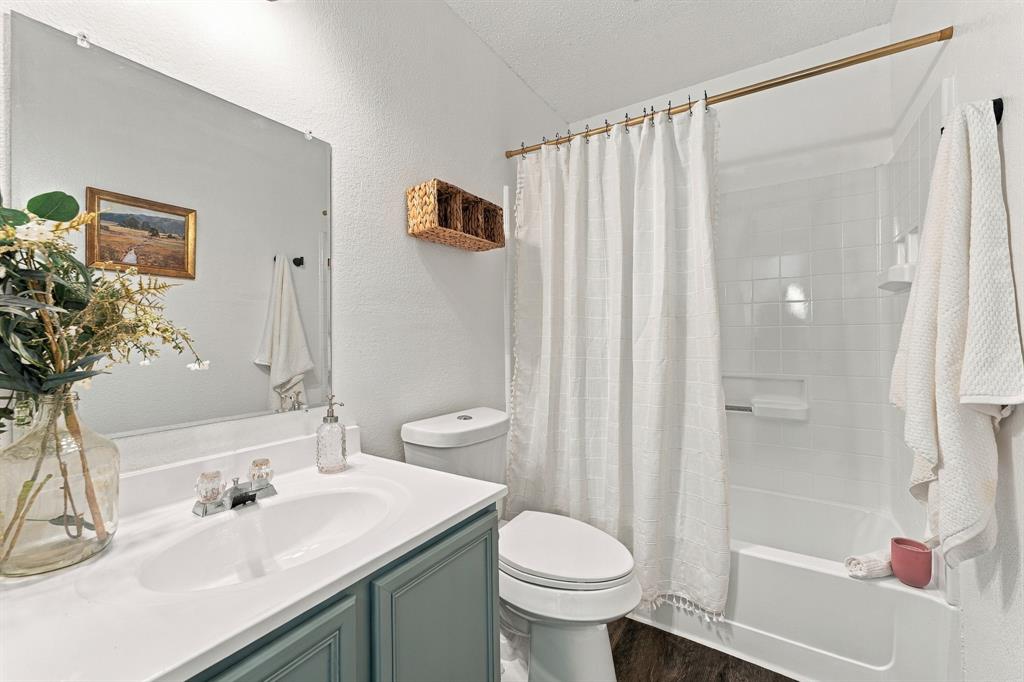 Bathroom featuring a vanity with a white countertop and integrated sink, frameless wall-mounted mirror, and a tub-shower combination with white tile surround