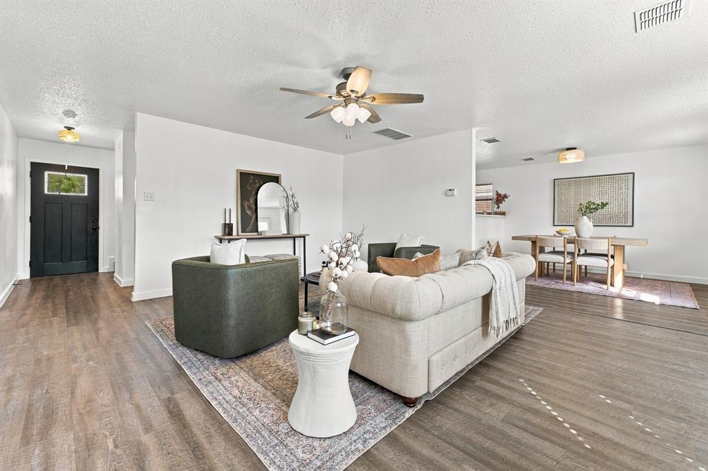 Living area featuring wood-finish flooring, a ceiling fan with integrated lighting, and a black front door with a glass inlay